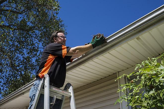 maintenance worker using a ladder to repair a gutter in Ceres CA